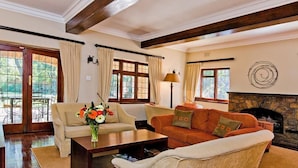 A cozy living room with a fireplace, two sofas, a coffee table, and a dining area with chairs. - Eagle Wind Manor (Botha's Hill)