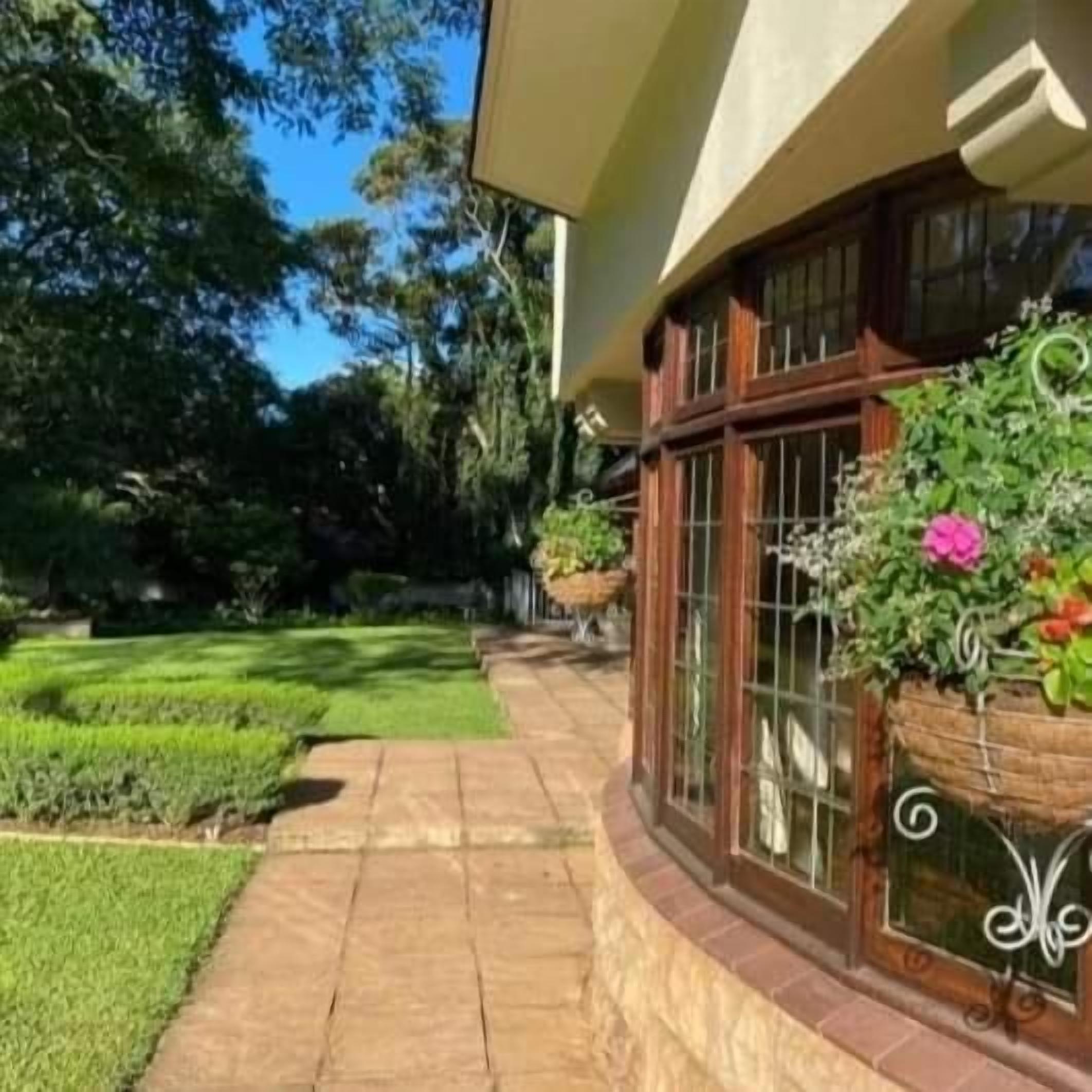 Una casa con techo curvo, ventanas amplias y un jardín cuidado con un camino pavimentado.