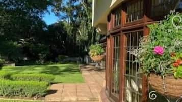 Una casa con techo curvo, ventanas amplias y un jardín cuidado con un camino pavimentado.