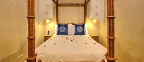 A four-poster bed with a canopy, white bedding, and decorative pillows.