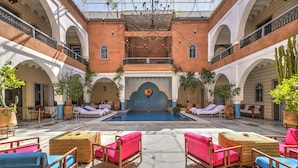 Un patio con piscina, mobiliario exterior y una fuente central.
