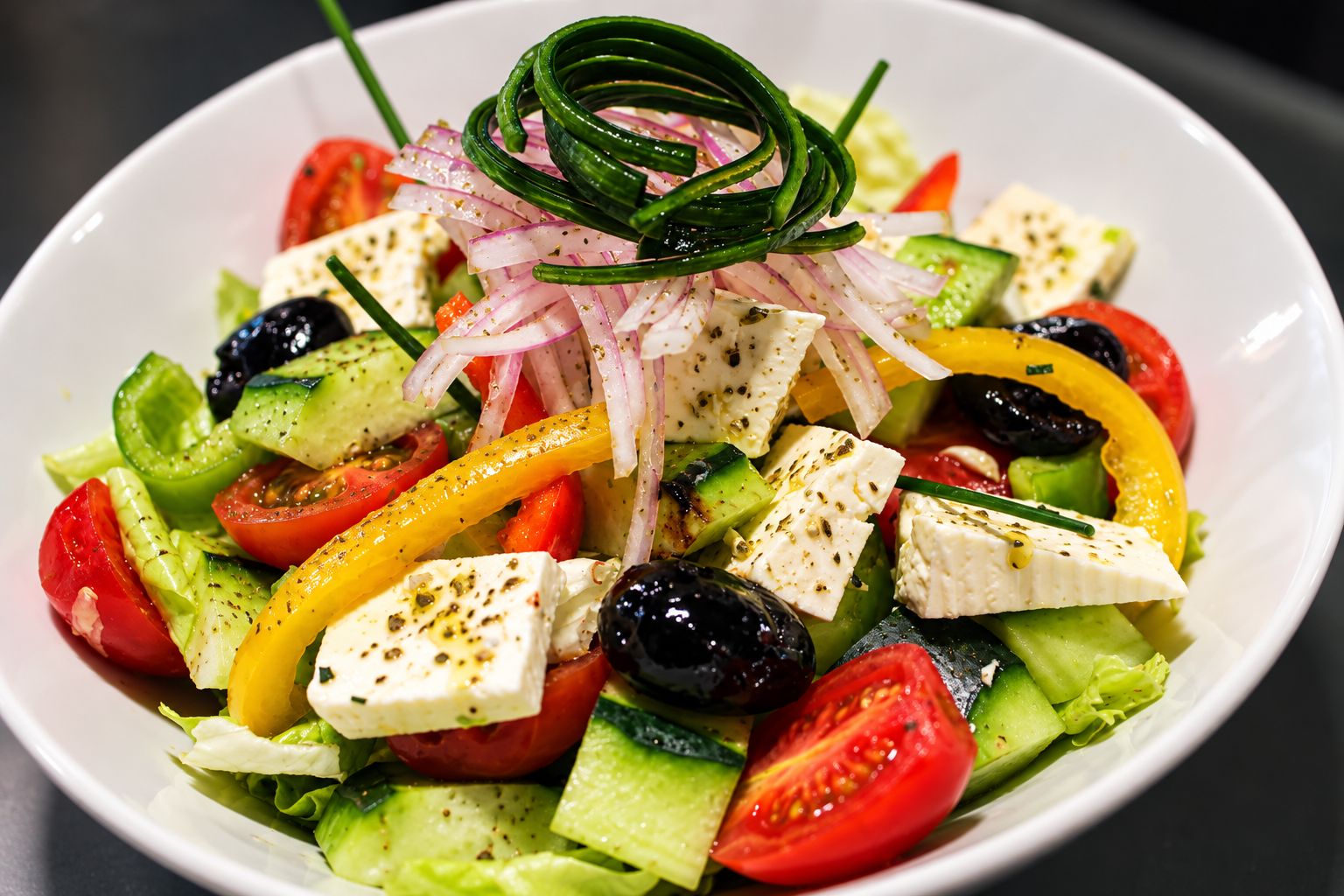 A bowl of salad with various vegetables and cheese.