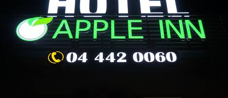 Un letrero de neón del Hotel Apple Inn con el nombre y número de teléfono.