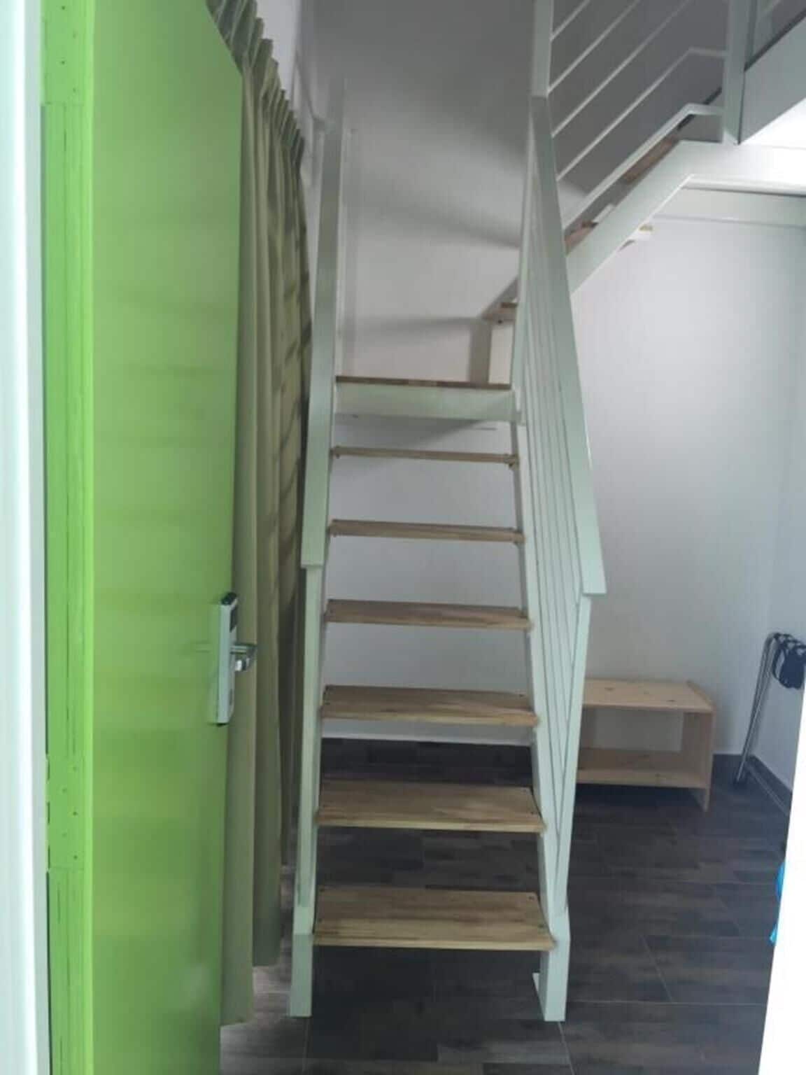 Eine Treppe mit Holzstufen und einer grünen Tür links.