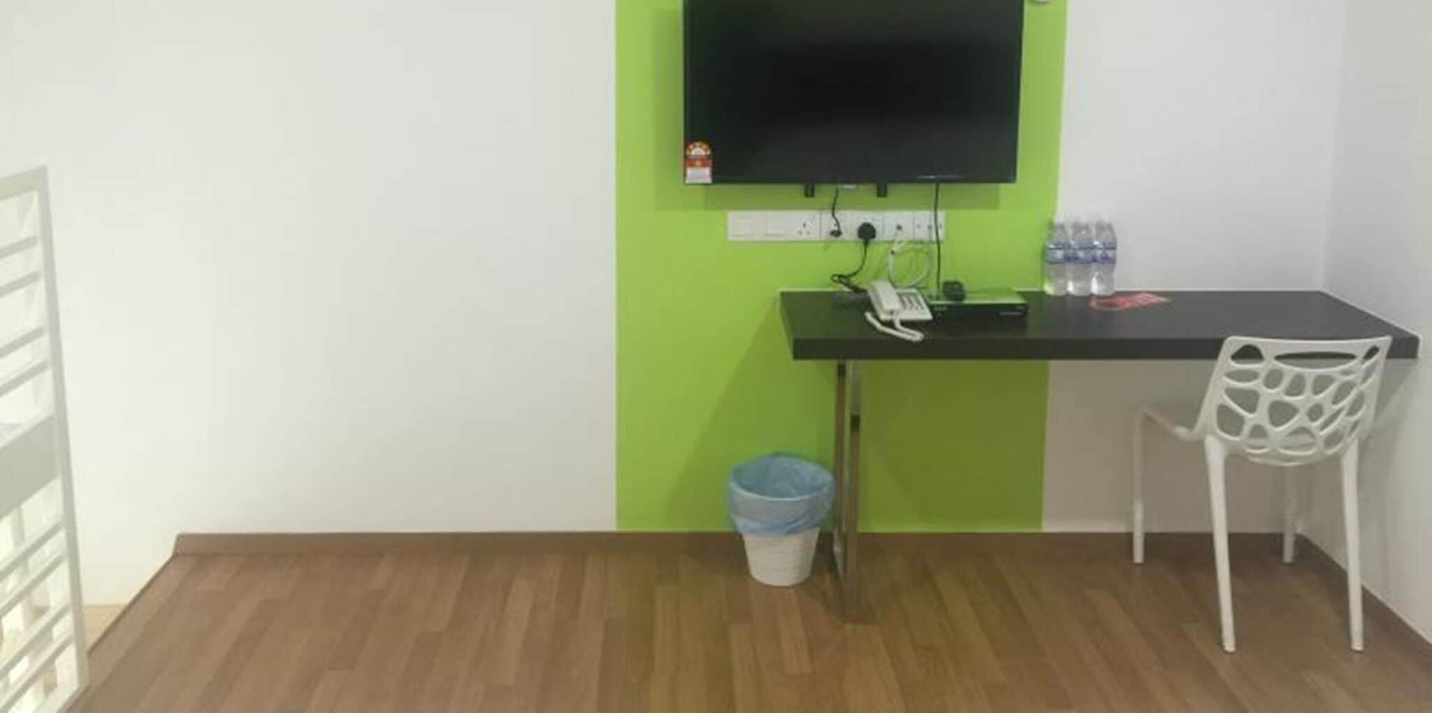 A small office space with a desk, chair, and a television mounted on the wall.