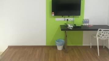 A small office space with a desk, chair, and a television mounted on the wall.