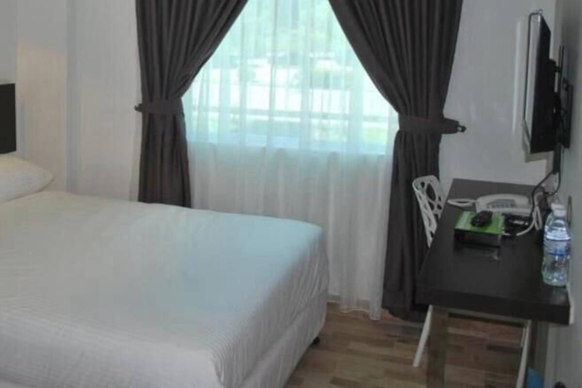 A hotel room with a bed, a desk with a phone, and a TV.