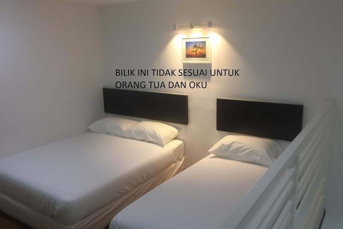 A hotel room with two single beds, a nightstand, and a wall-mounted light fixture.