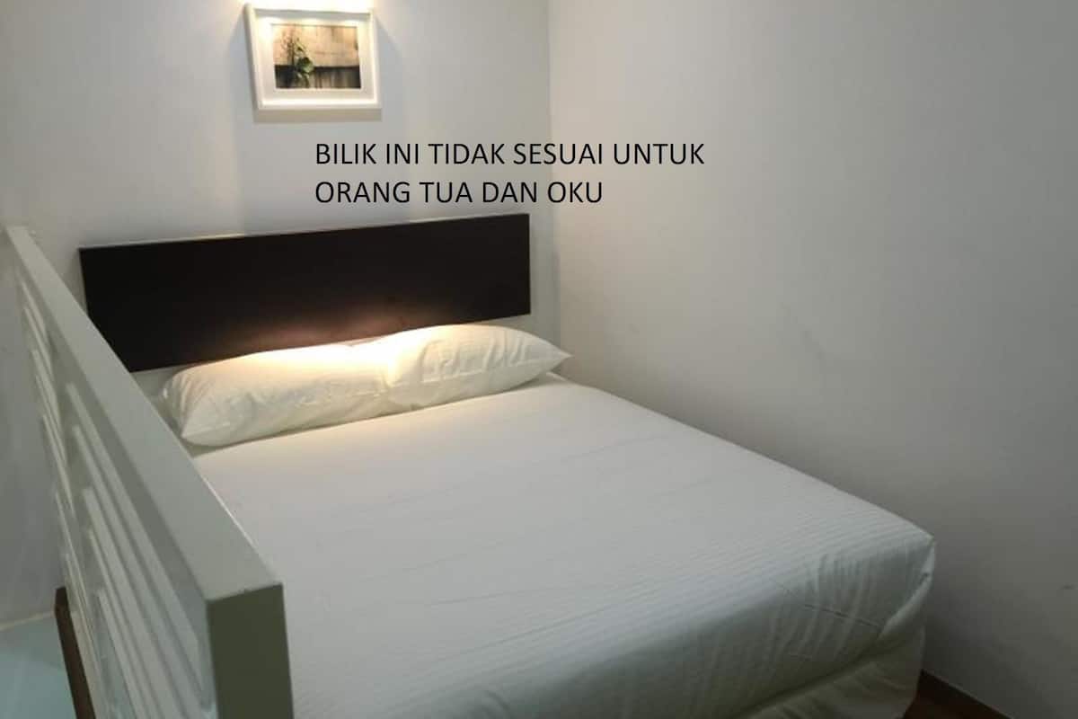 A neatly made bed in a room with a white wall and a framed picture above it.