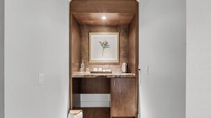 Eine schmale Küche mit Holzausbau, einer Marmorarbeitsplatte und einem gerahmten Pflanzenprint an der Wand.