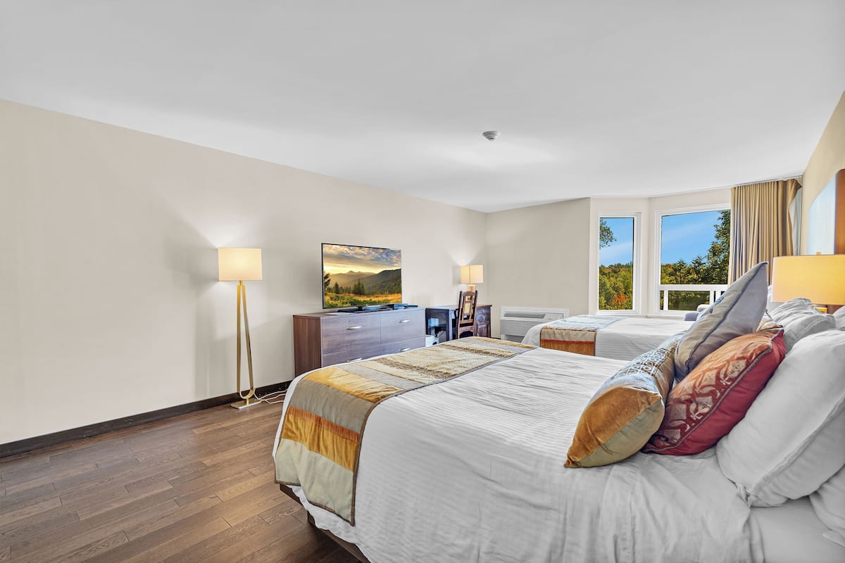 A hotel room with a large bed, a desk, a chair, and a TV.