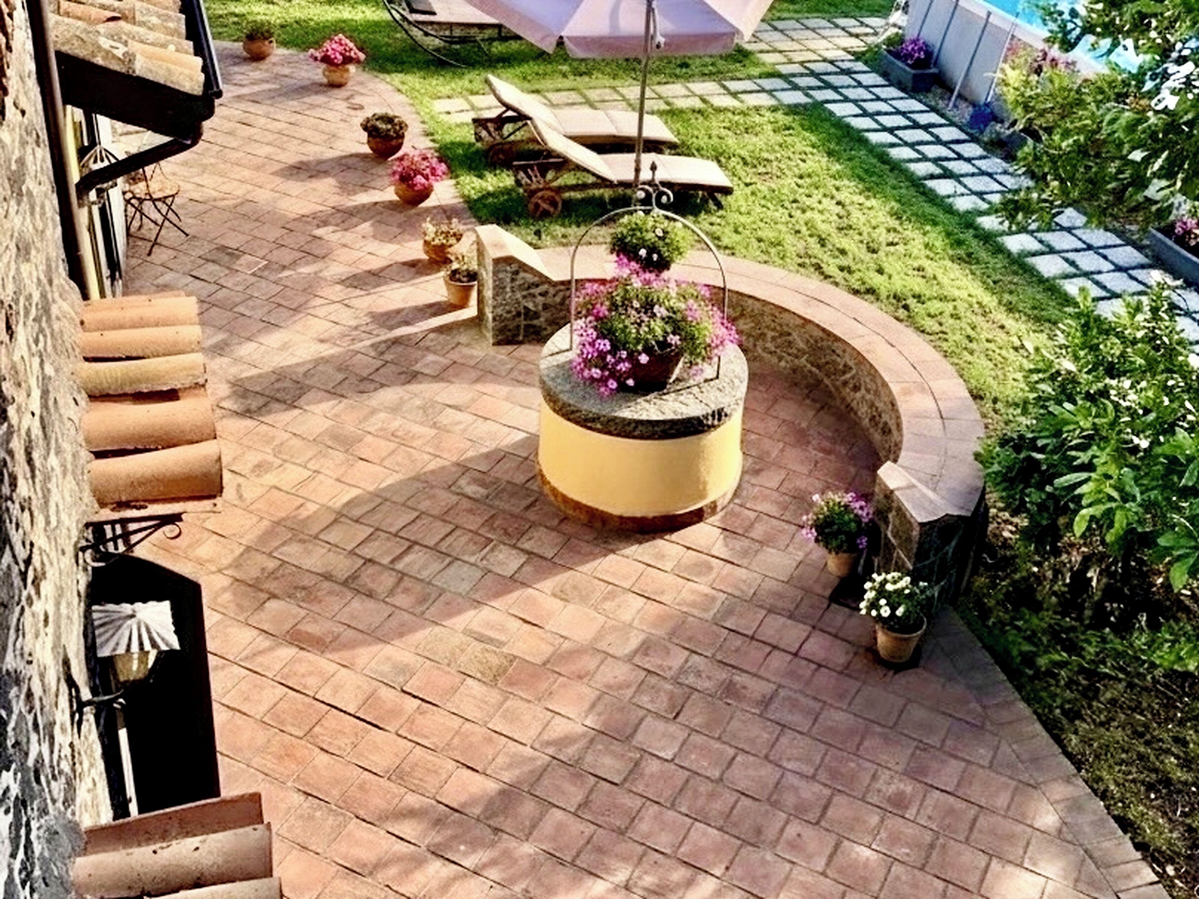 A patio with a circular planter, outdoor furniture, and a stone wall.