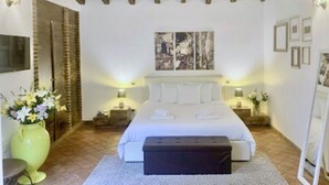 A bedroom with a bed, bedside tables, a large vase with flowers, and a painting on the wall. - B&B Villa Loriana (Milo)