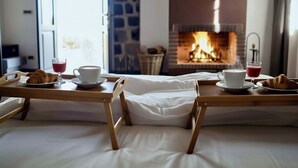A cozy room with a bed, a breakfast tray with croissants and drinks, and a fireplace in the background. - B&B Villa Loriana (Milo)