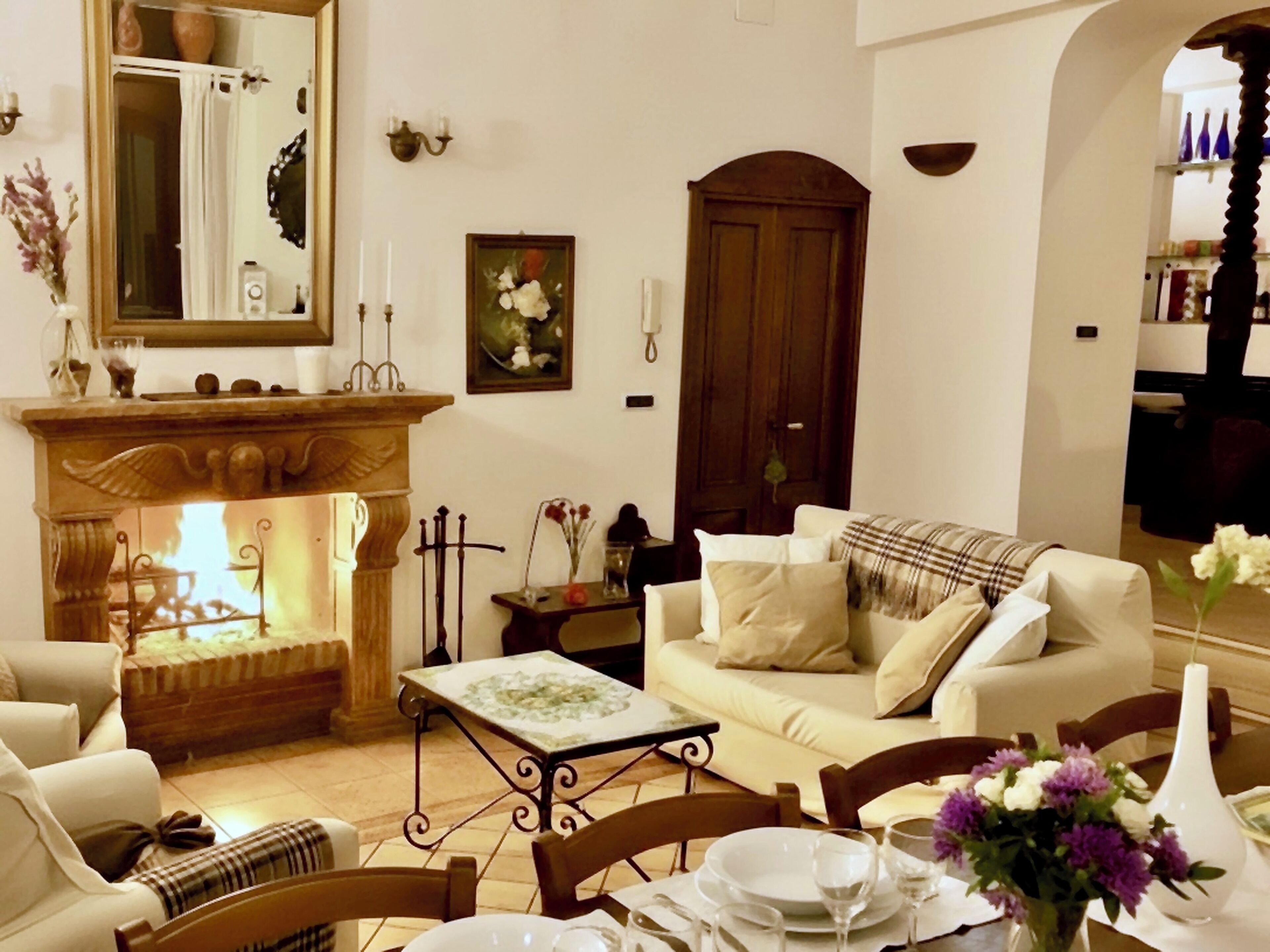 Un salón acogedor con chimenea, un sofá, una mesa de comedor para dos personas y una estantería al fondo.