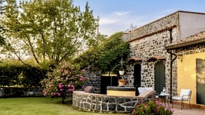 A stone building with a stone wall and a small patio area with a table and chairs. - B&B Villa Loriana (Milo)