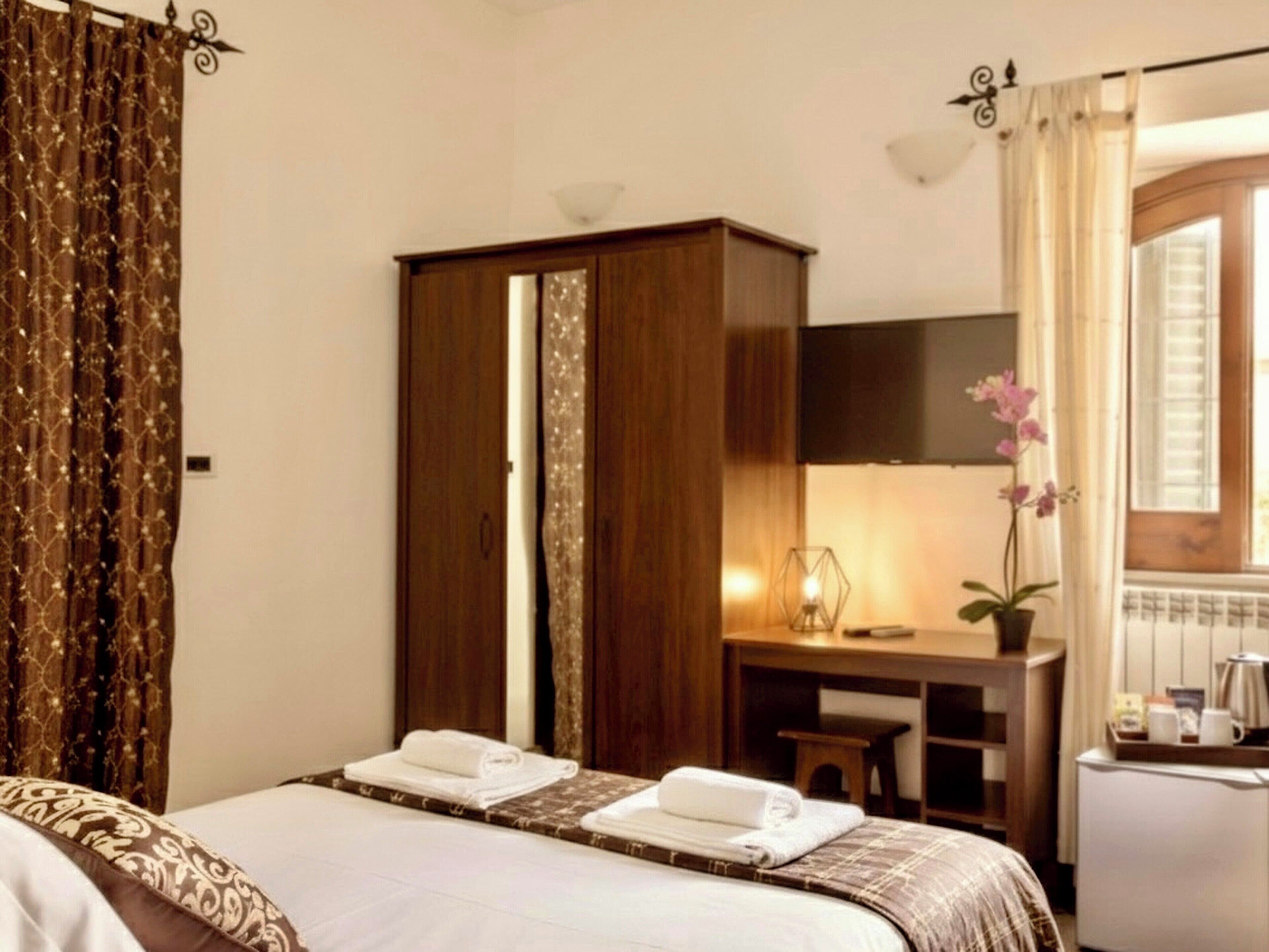 A hotel room with a bed, a desk, a wardrobe, and a bathroom visible through an open door.