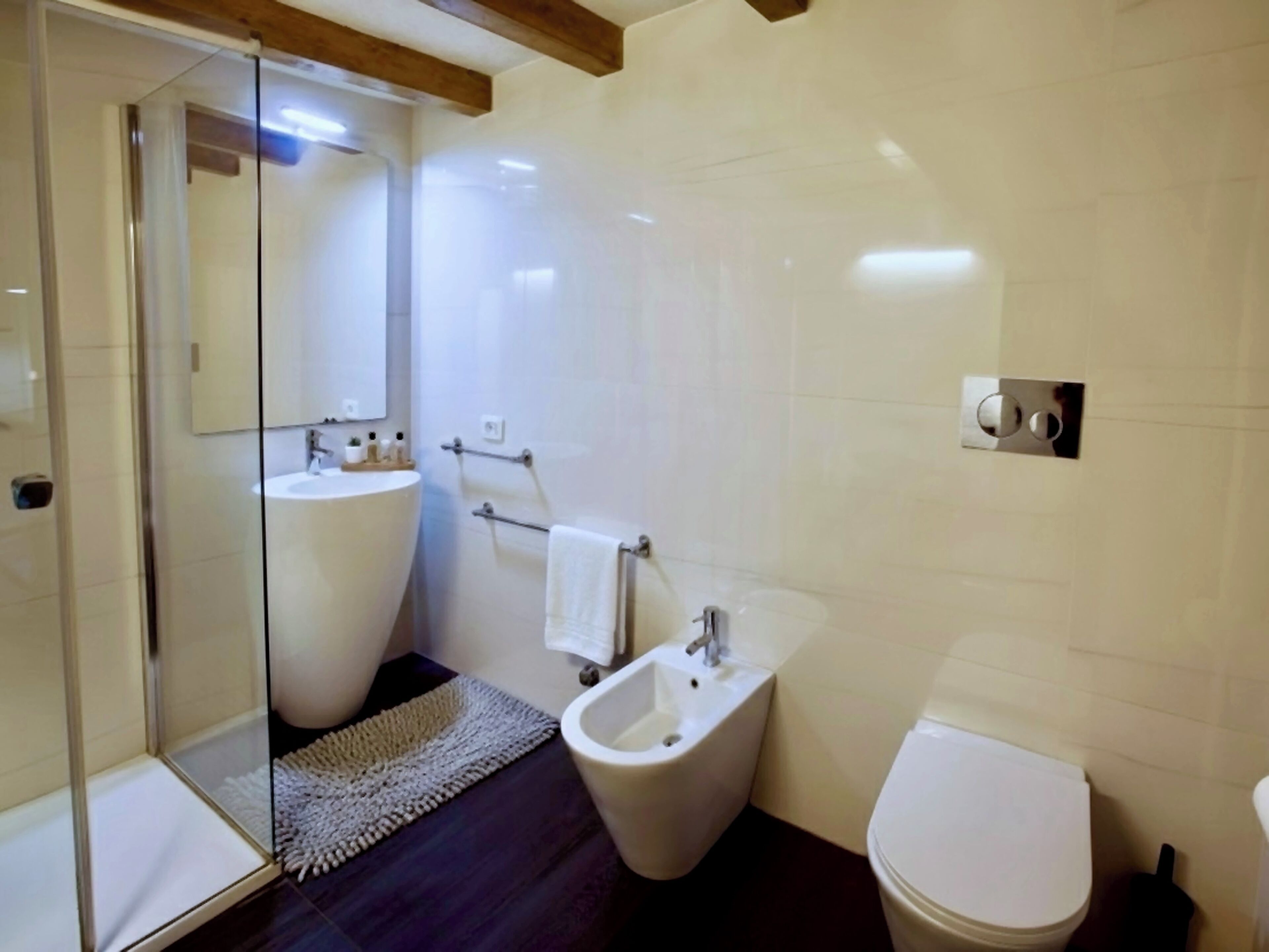 Un baño con cabina de ducha de vidrio, un bidé, un inodoro y un lavabo.