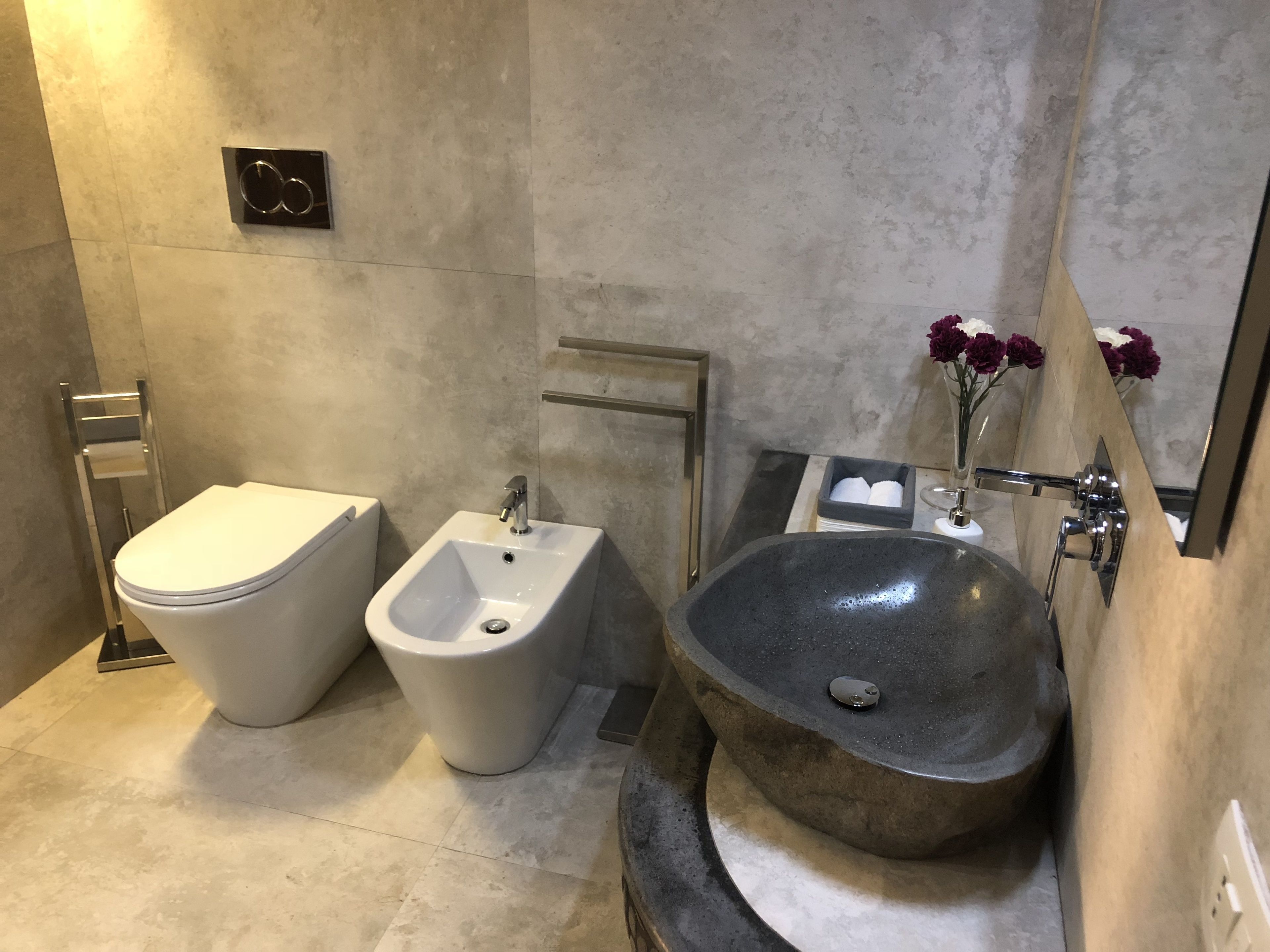Een moderne badkamer met toilet, bidet en een ruime wastafel.