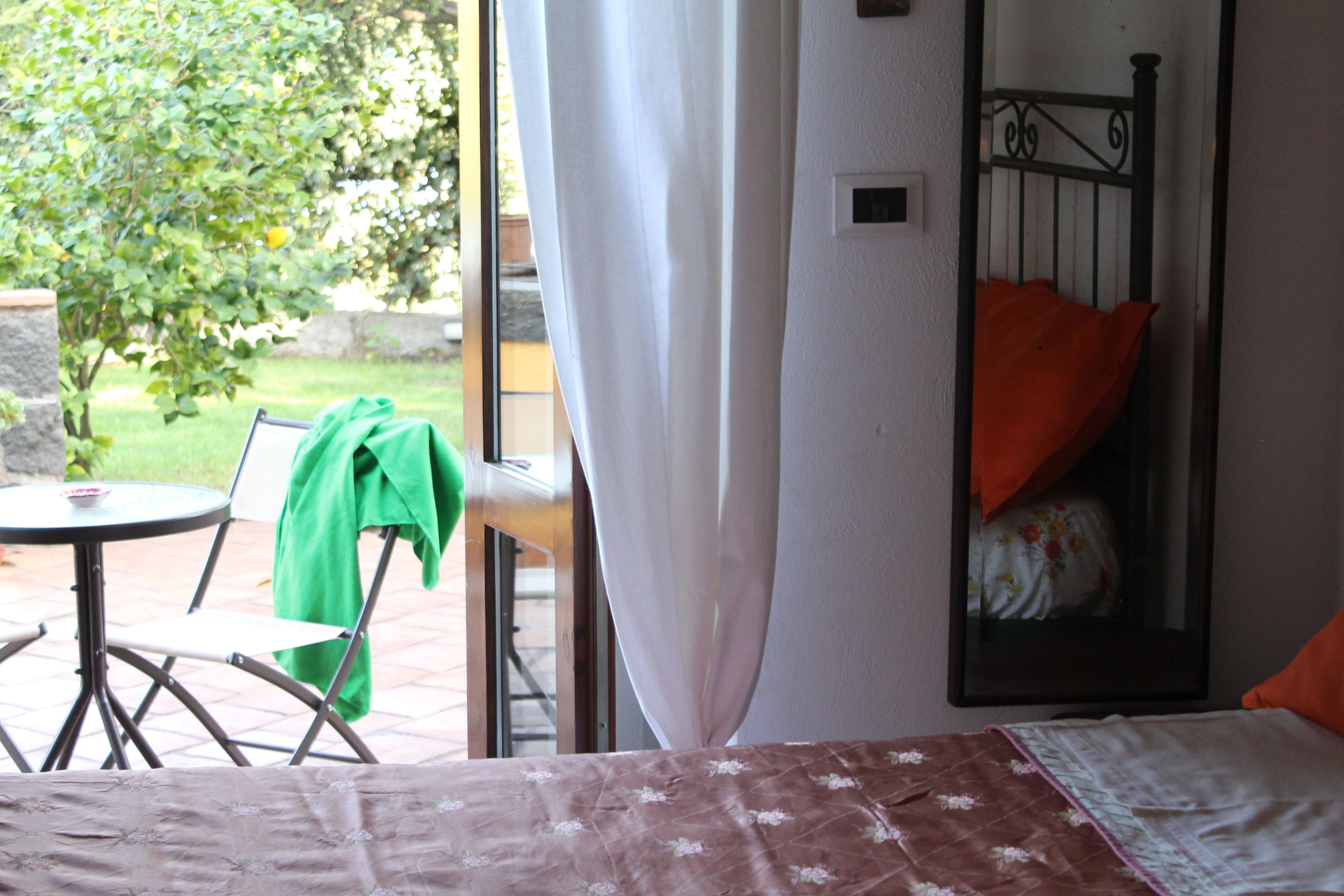 Ein Zimmer mit einem Bett, einem Sessel, einem Tisch und einem Fenster mit Vorhängen.