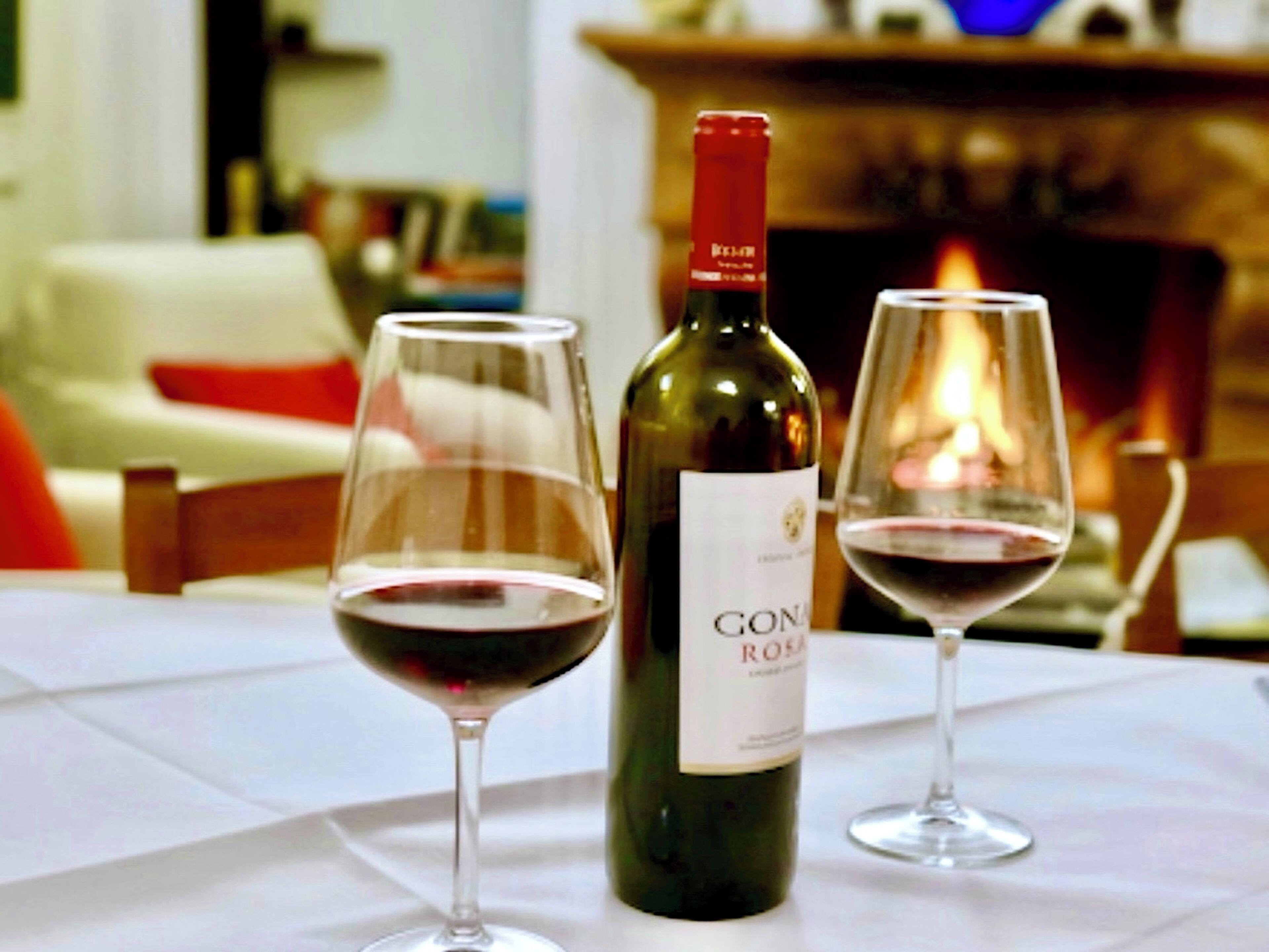 A table with a bottle of wine and two glasses of wine.