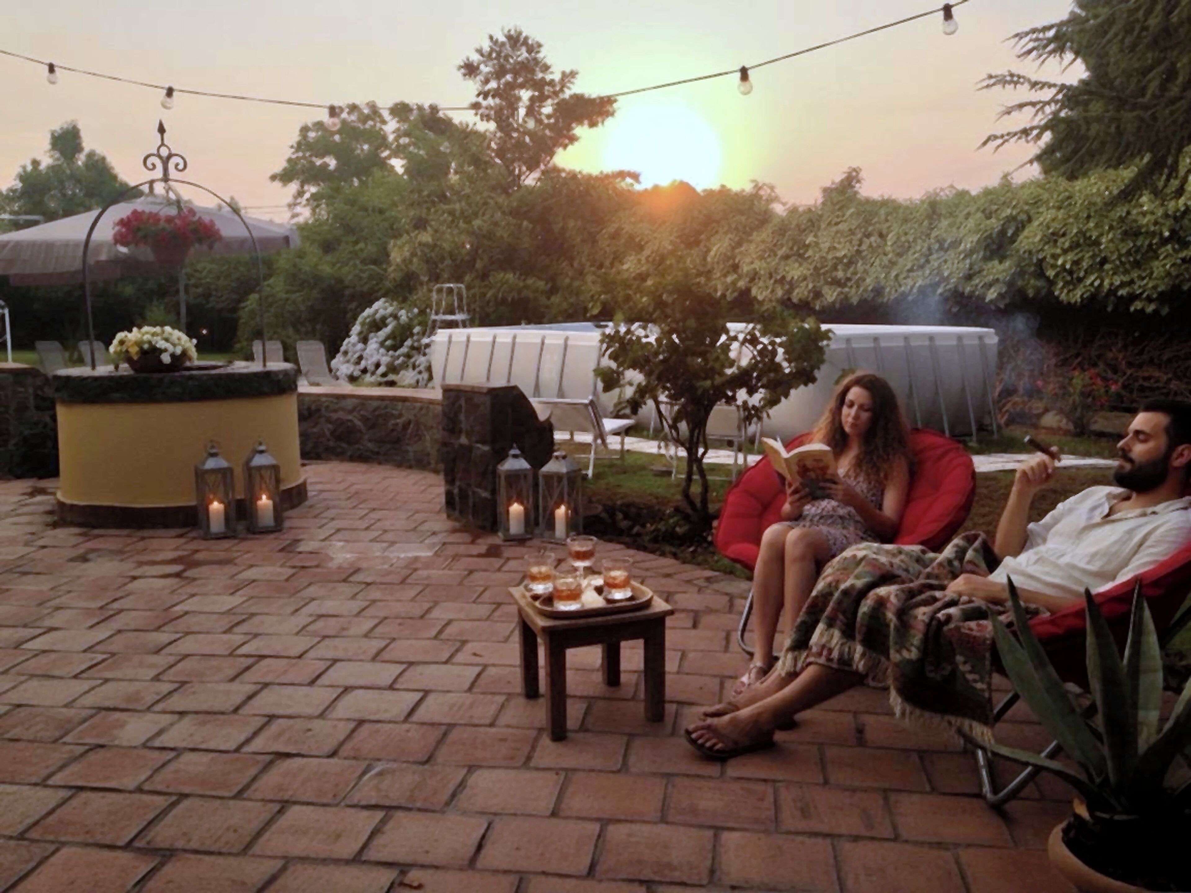An outdoor patio with brick flooring, a round table with candles, and string lights.