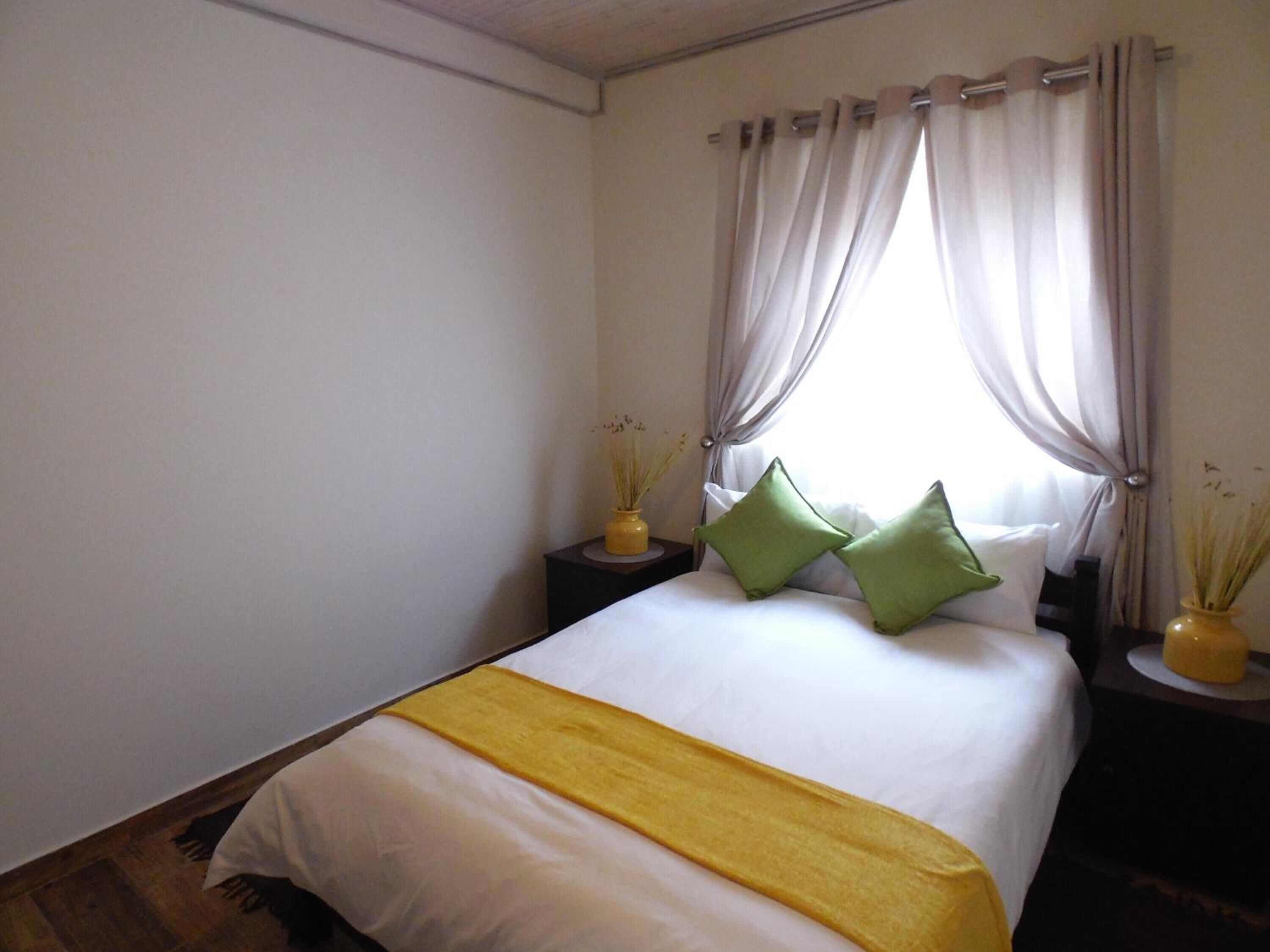 A bedroom with a bed, curtains, pillows, and bedside tables.