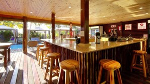 Une terrasse en bois avec un espace bar comprenant des tabourets et un comptoir.