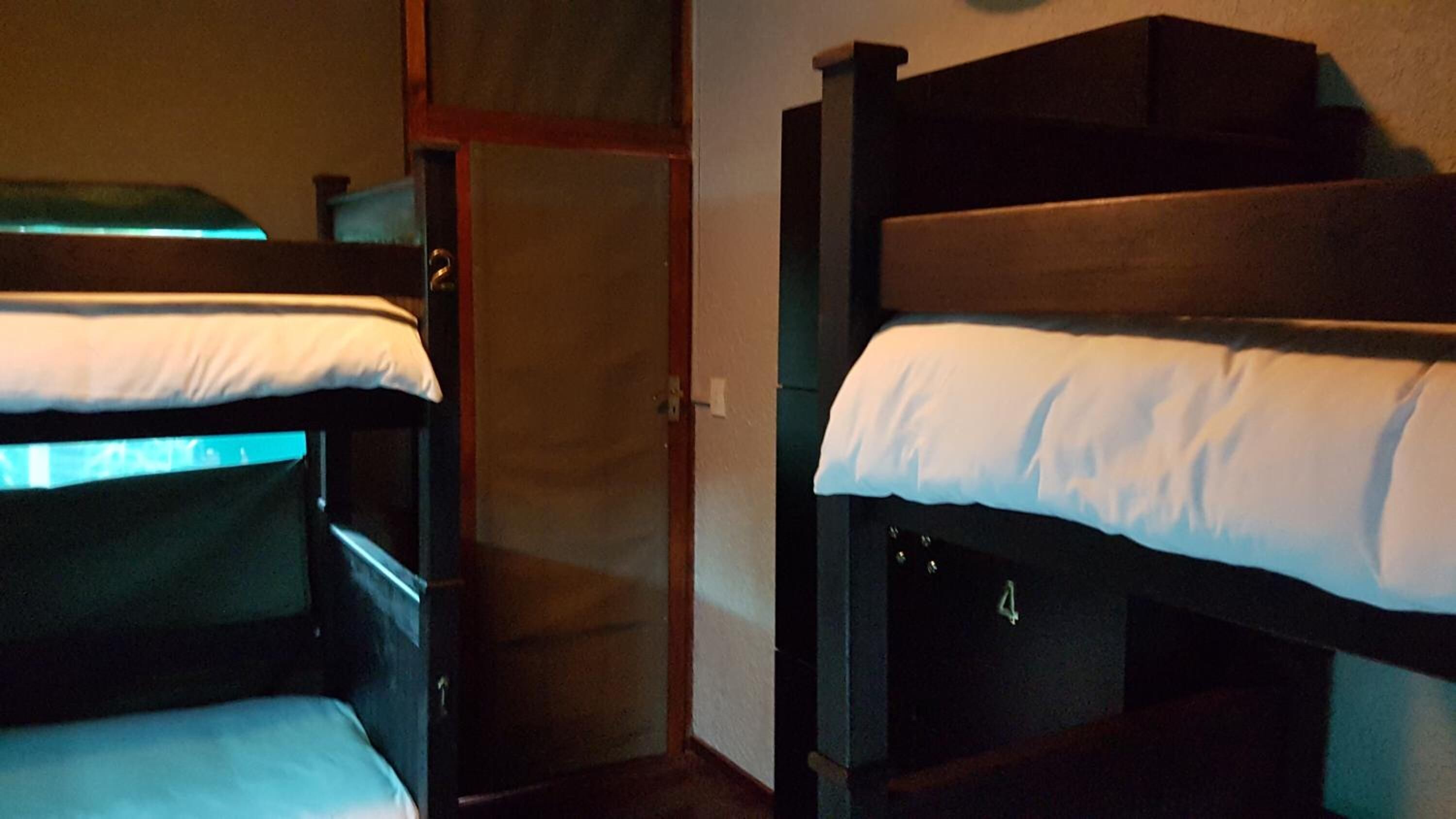 Una habitación con dos literas, una puerta de madera y un mueble pequeño.