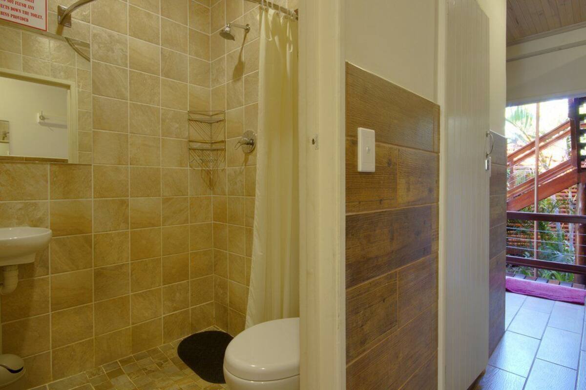 Une salle de bain avec douche, toilettes et lavabo.