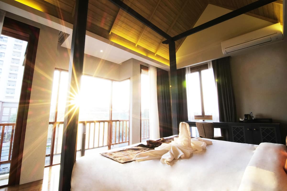 A hotel room with a large bed, a desk, and a view of the outside.