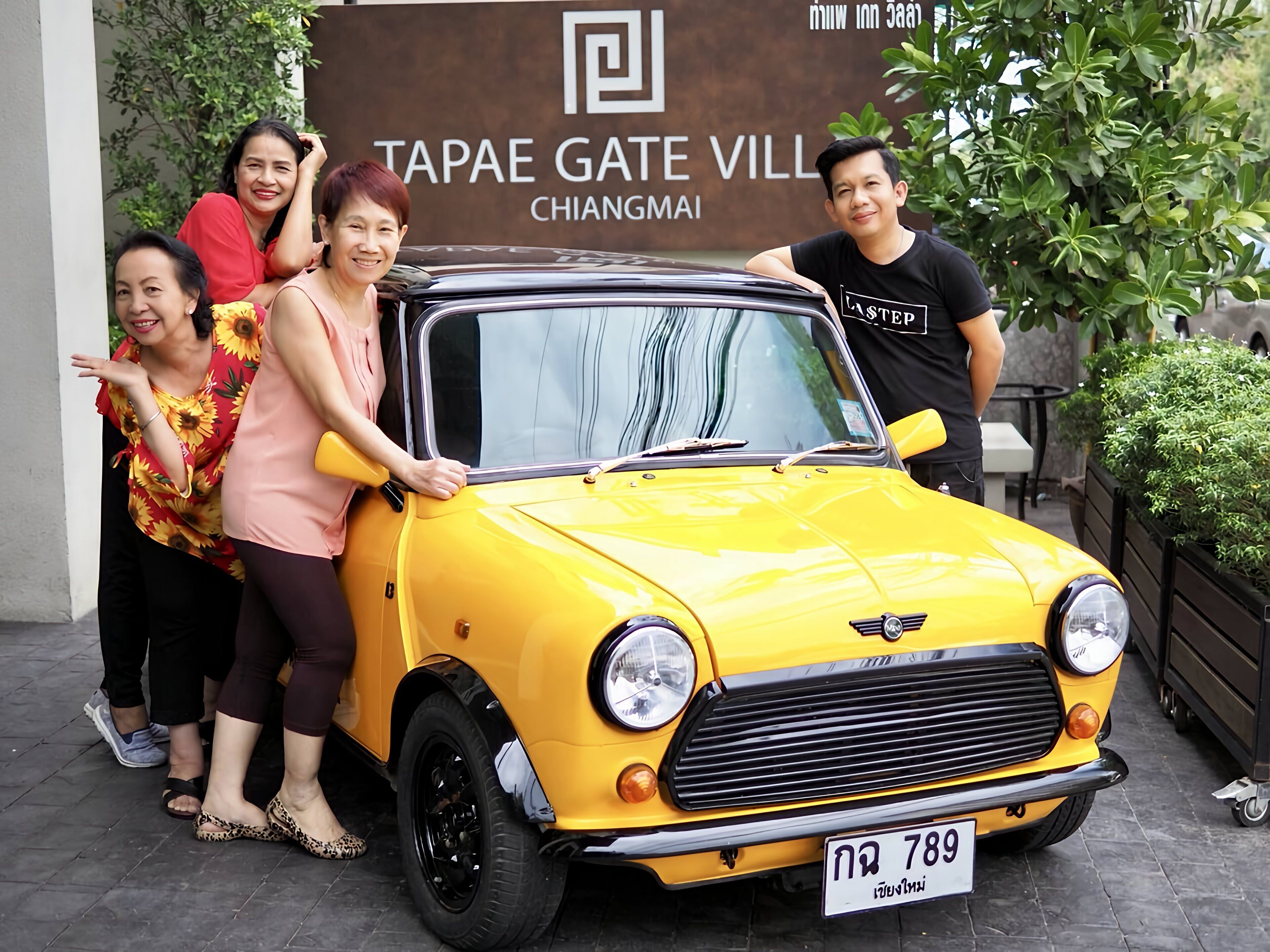 A yellow car parked in front of a sign that reads "TAPAE GATE VILL CHIANGMAI".