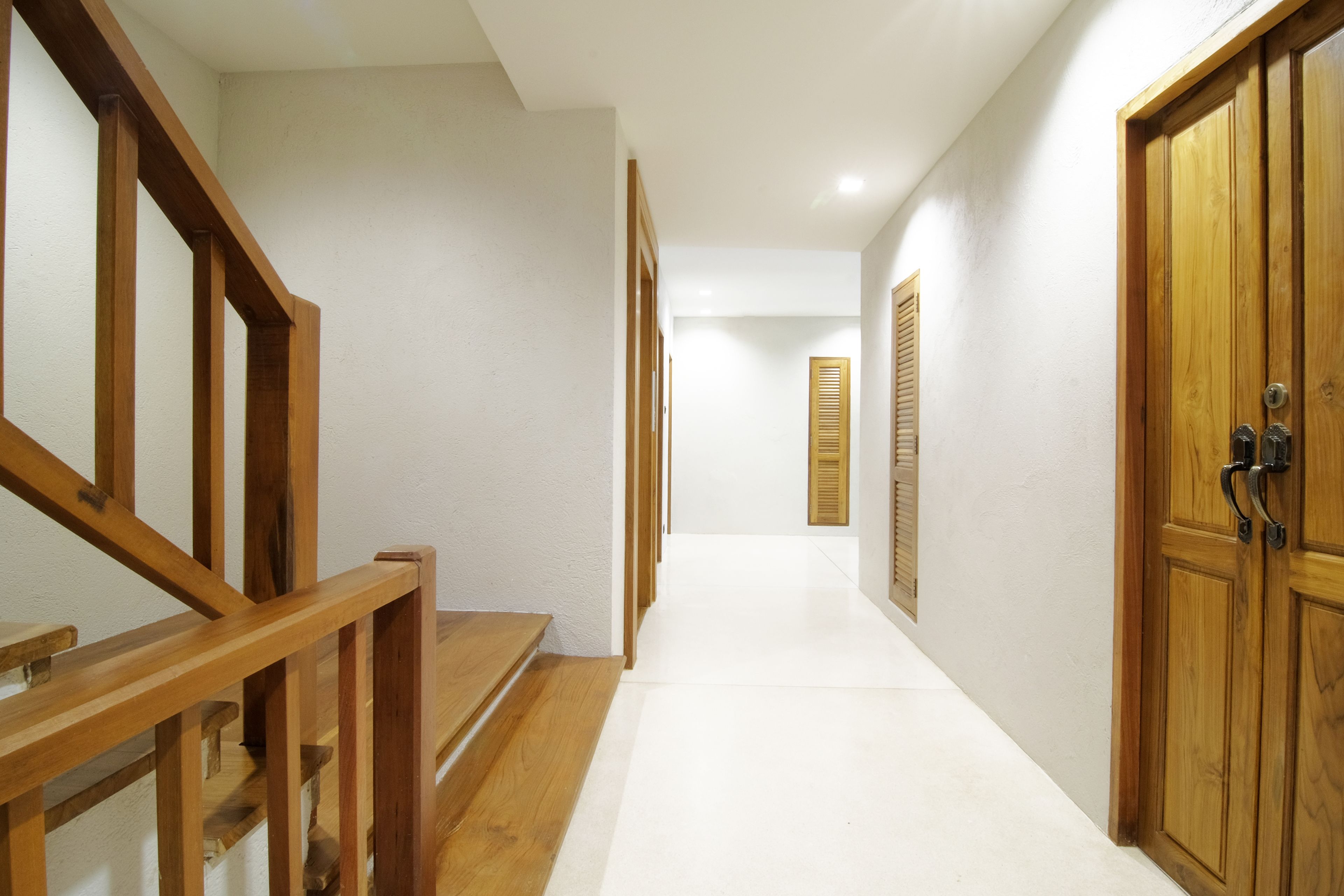 A hallway with wooden stairs, a door, and a window with shutters.