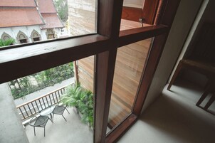 A balcony with a wooden railing, a glass table, and two chairs.