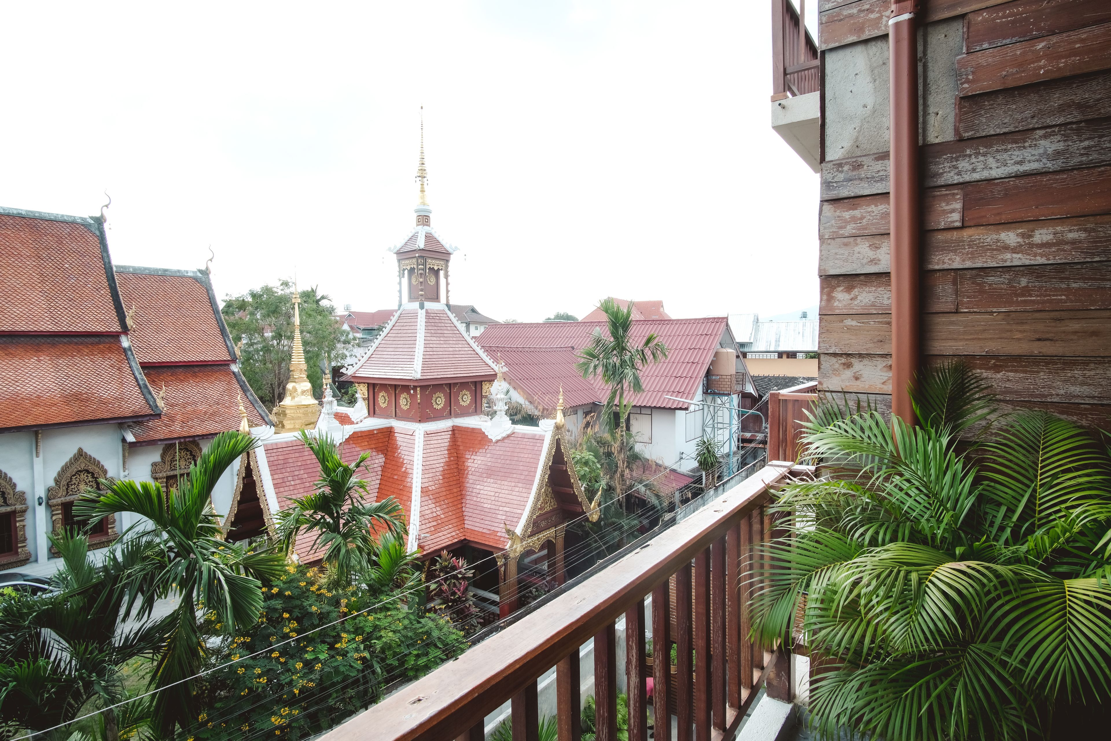 A traditional temple with a golden spire, surrounded by lush greenery and red-roofed buildings.
