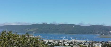 A coastal town with a marina, buildings, and hills in the background.