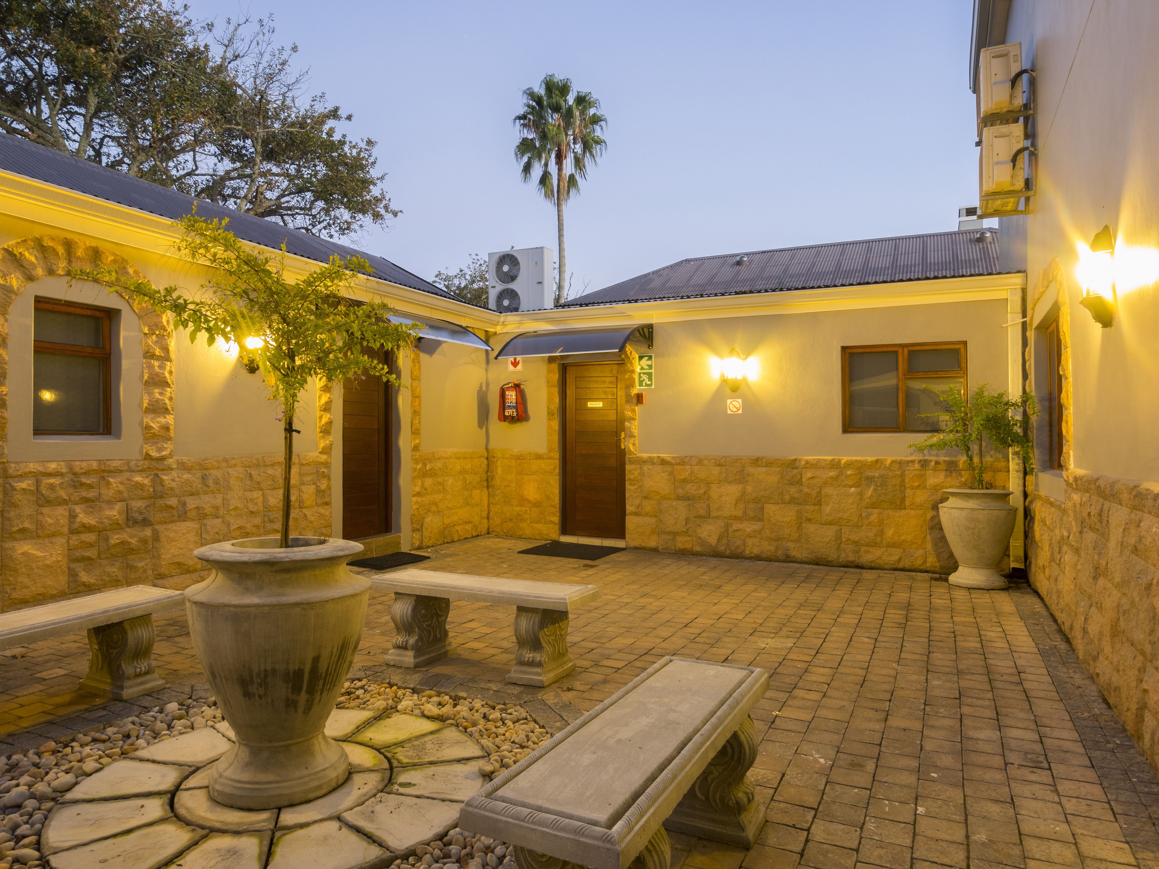 A courtyard with stone walls, a large planter, and a bench.