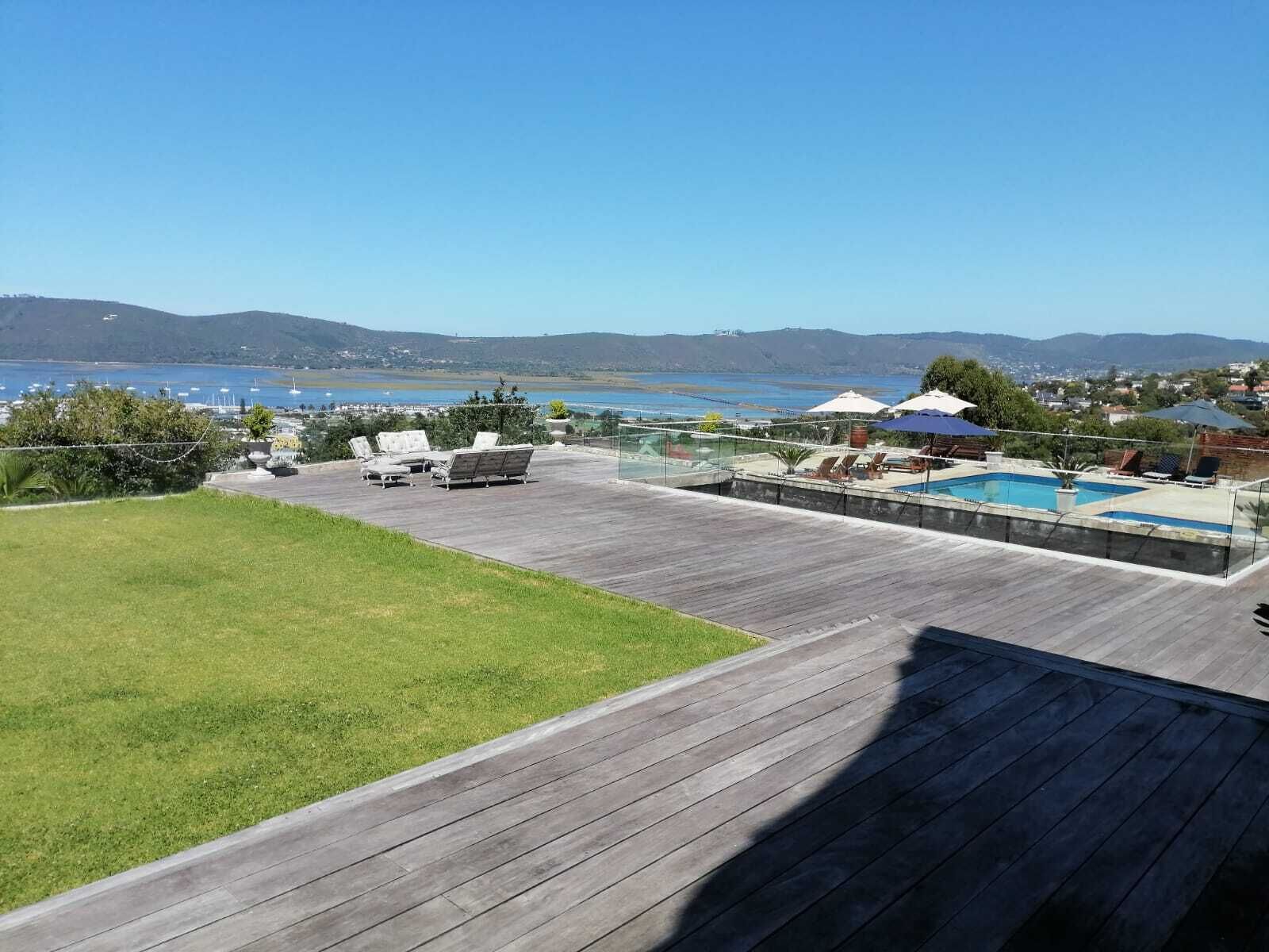 Una terraza con piscina, sillones de descanso y vistas al mar y a las colinas.