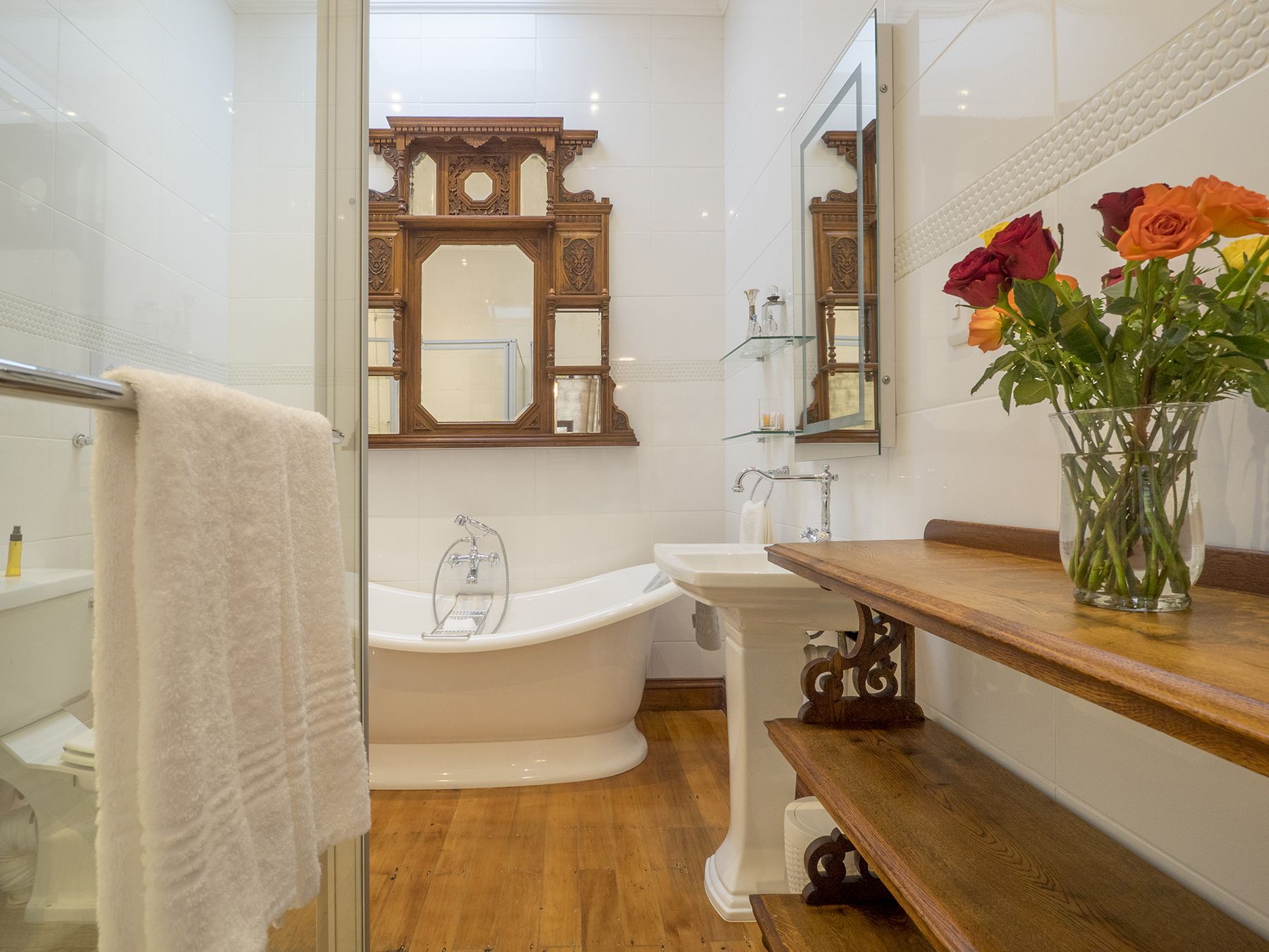Un baño con una bañera independiente, un lavabo y un mueble de tocador con un jarrón de flores.