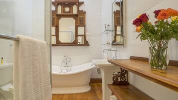 Un baño con una bañera independiente, un lavabo y un mueble de tocador con un jarrón de flores.