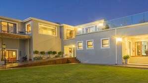 Uma casa moderna de dois andares com um gramado bem cuidado, uma varanda e uma entrada frontal com degraus.