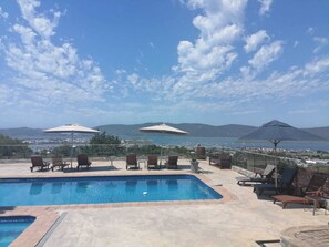A pool area with lounge chairs and umbrellas, overlooking a body of water and distant mountains. - Issaquena Heights Boutique Hotel (Knysna)