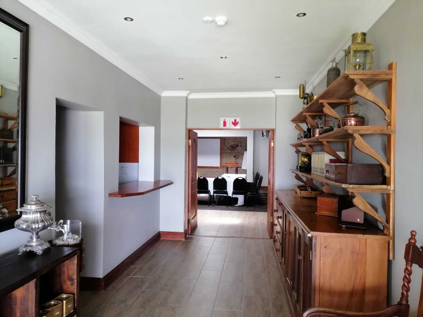 Un couloir avec une armoire en bois sur la droite, un miroir sur la gauche et une porte donnant sur une salle à manger.