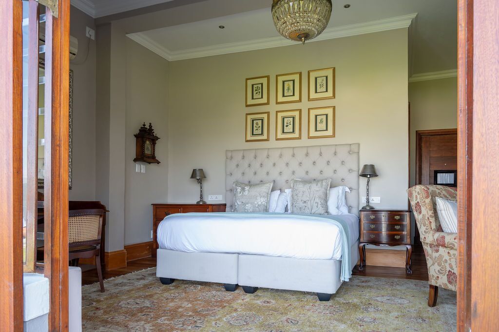 A bedroom with a large bed, a nightstand, a dresser, a chair, and a chandelier.