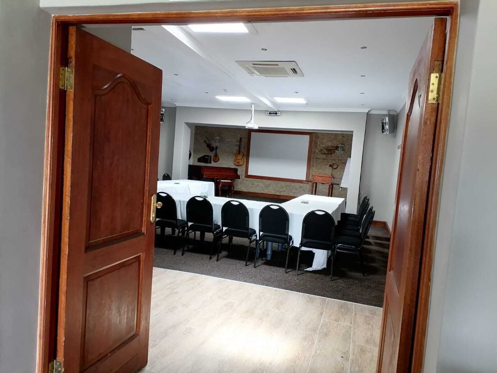A conference room with a long table, black chairs, and a whiteboard.