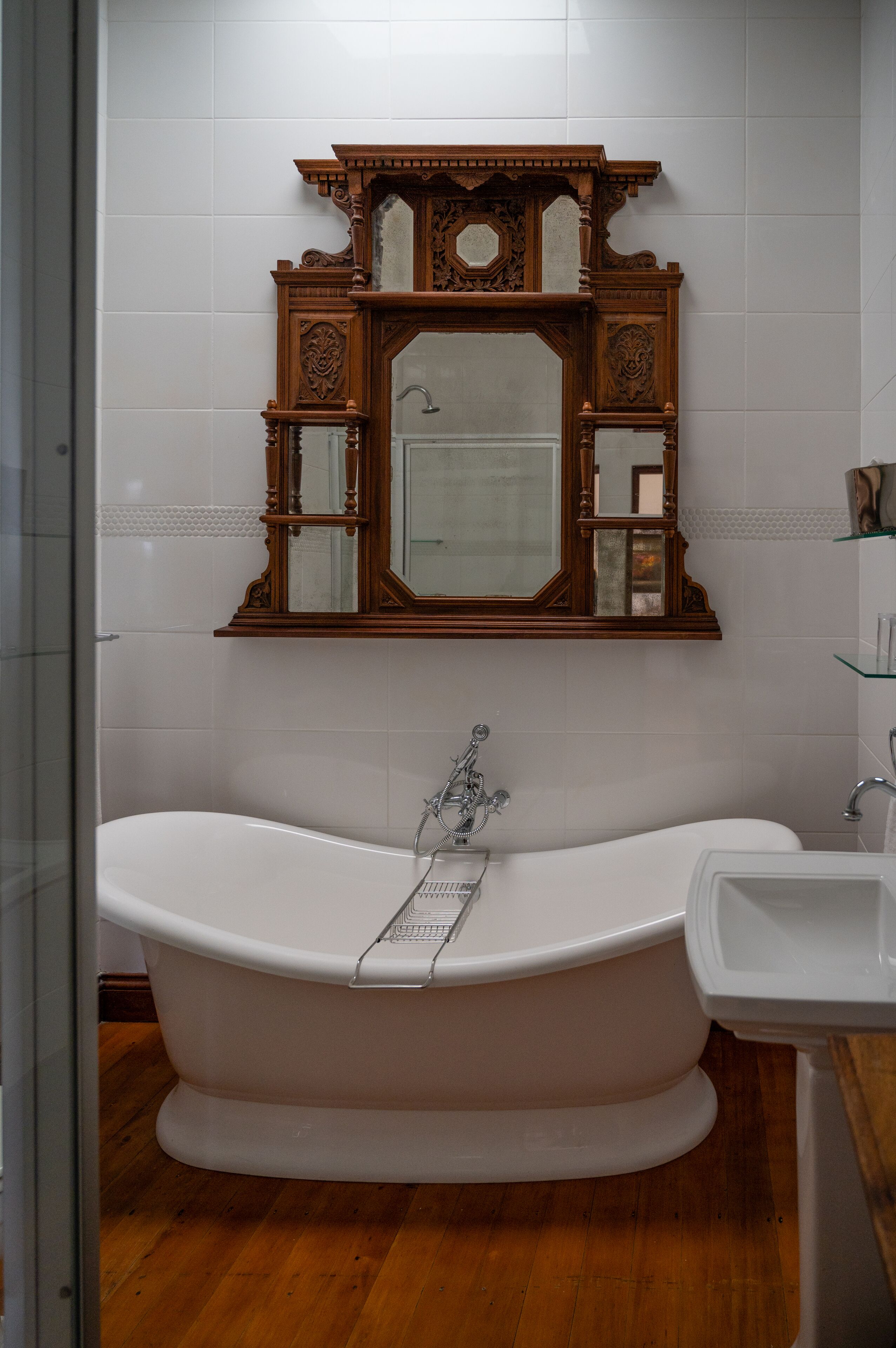 A bathroom with a freestanding bathtub, a wooden vanity with a mirror, and a white sink.