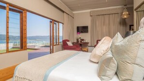 Quarto espaçoso com uma cama grande, uma escrivaninha e uma cadeira, com vista panorâmica através de amplas janelas.