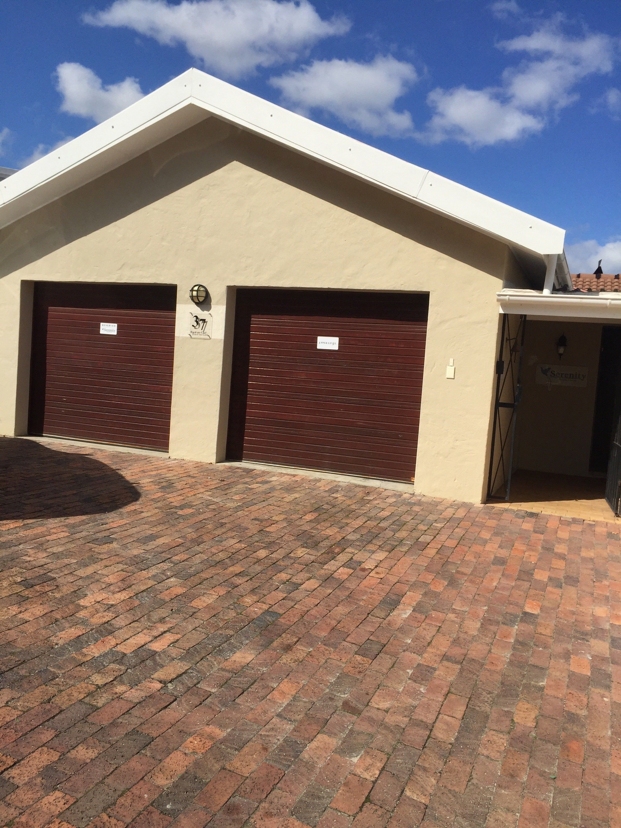 A building with two closed garage doors, a brick-paved entrance, and a clear blue sky.
