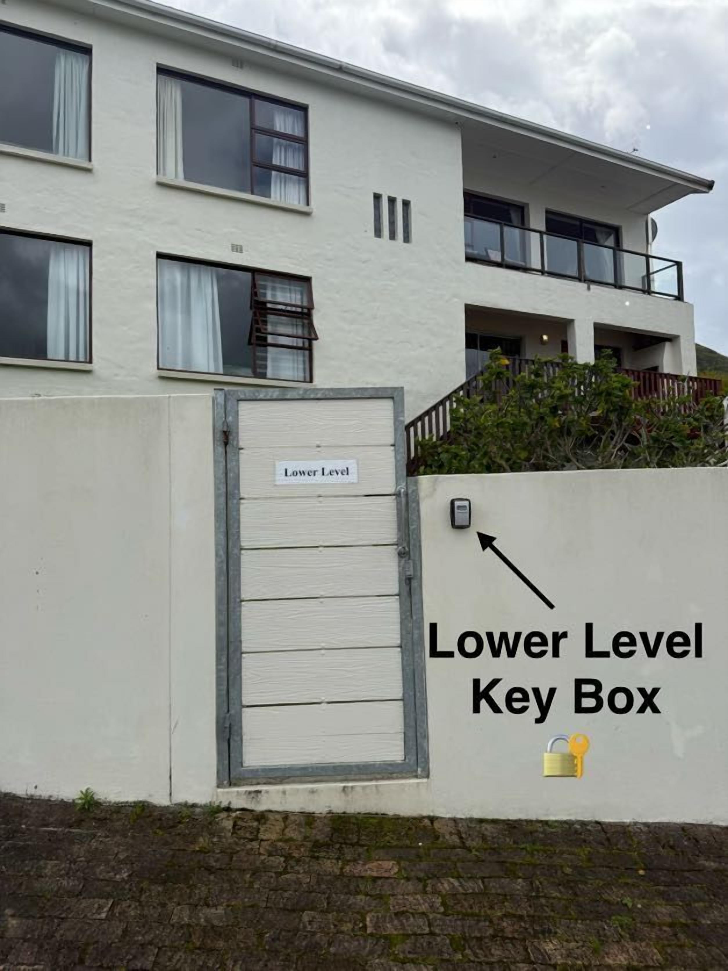 Un edificio con facciata bianca, una porta con l'indicazione 'Lower Level Key Box' e un cartello che vi punta.