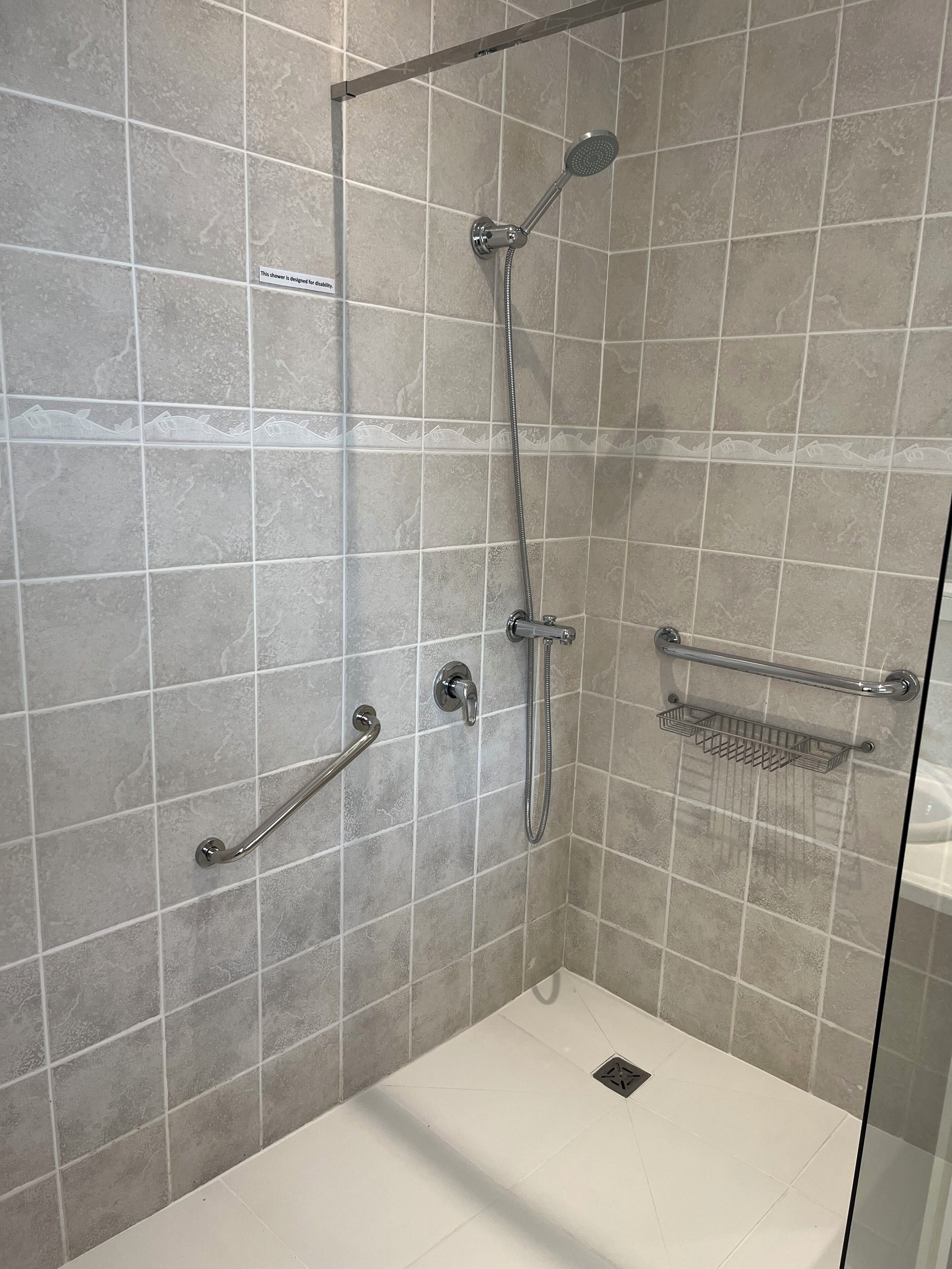 A modern shower with a handheld showerhead, a handheld shower attachment, and a handheld shower bar.